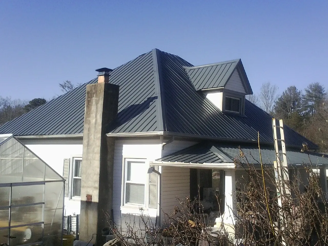 Dark blue standing seam metal roof on a white farmhouse with dormer — Slate & Tile Roof Repair by Roofing Brothers in Dinwiddie