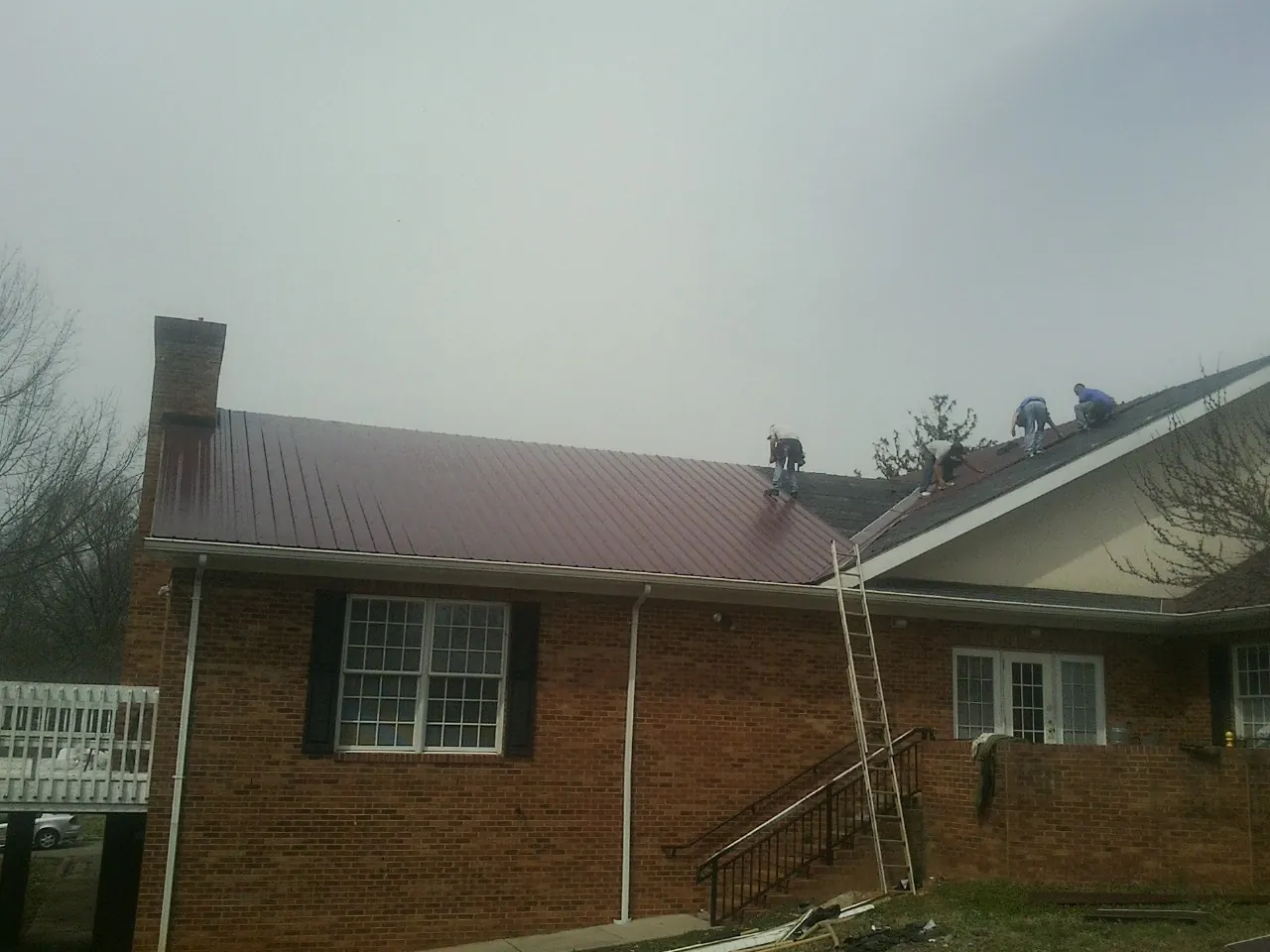 Crew setting red metal roofing panels on a brick home in Dinwiddie