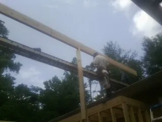 Carpenter setting a ridge beam over a new addition frame — Ice Dam Removal by Roofing Brothers in Dinwiddie