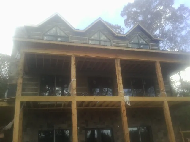 Dormers and porch framing on a large log home under construction — Roof Coating work by our crew in Dinwiddie