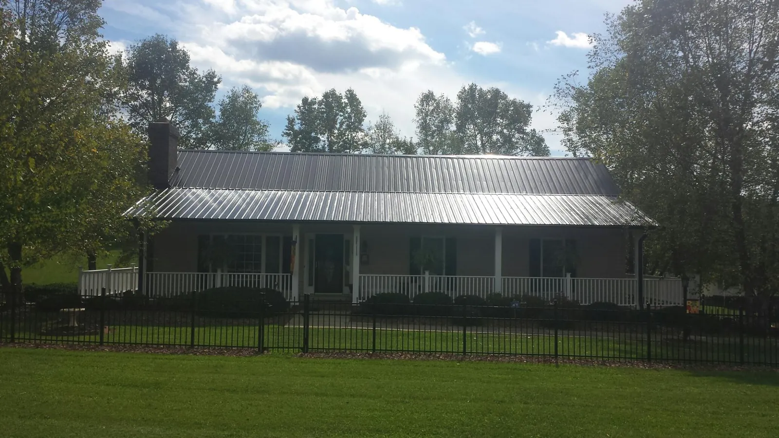 Gray metal roof on a brick ranch with a full width front porch — Gutter Guard Installation work by our crew in Dinwiddie