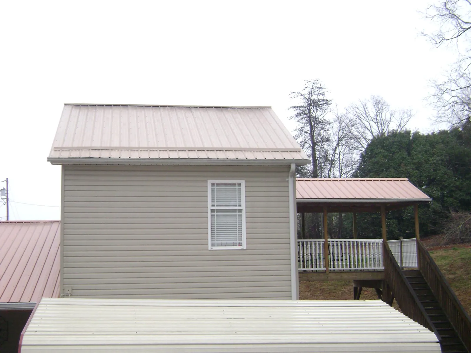Tan metal roofs on a two story addition and attached porch, from a Roof Replacement job in Dinwiddie