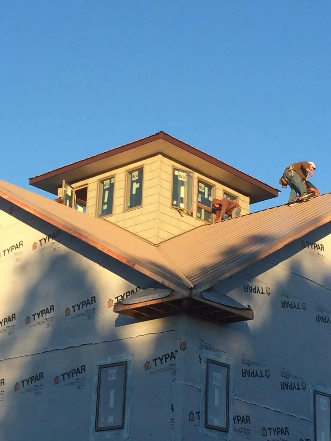 Roofers working around a rooftop cupola on a new metal roof at sunset — Roof Waterproofing in Dinwiddie by Roofing Brothers